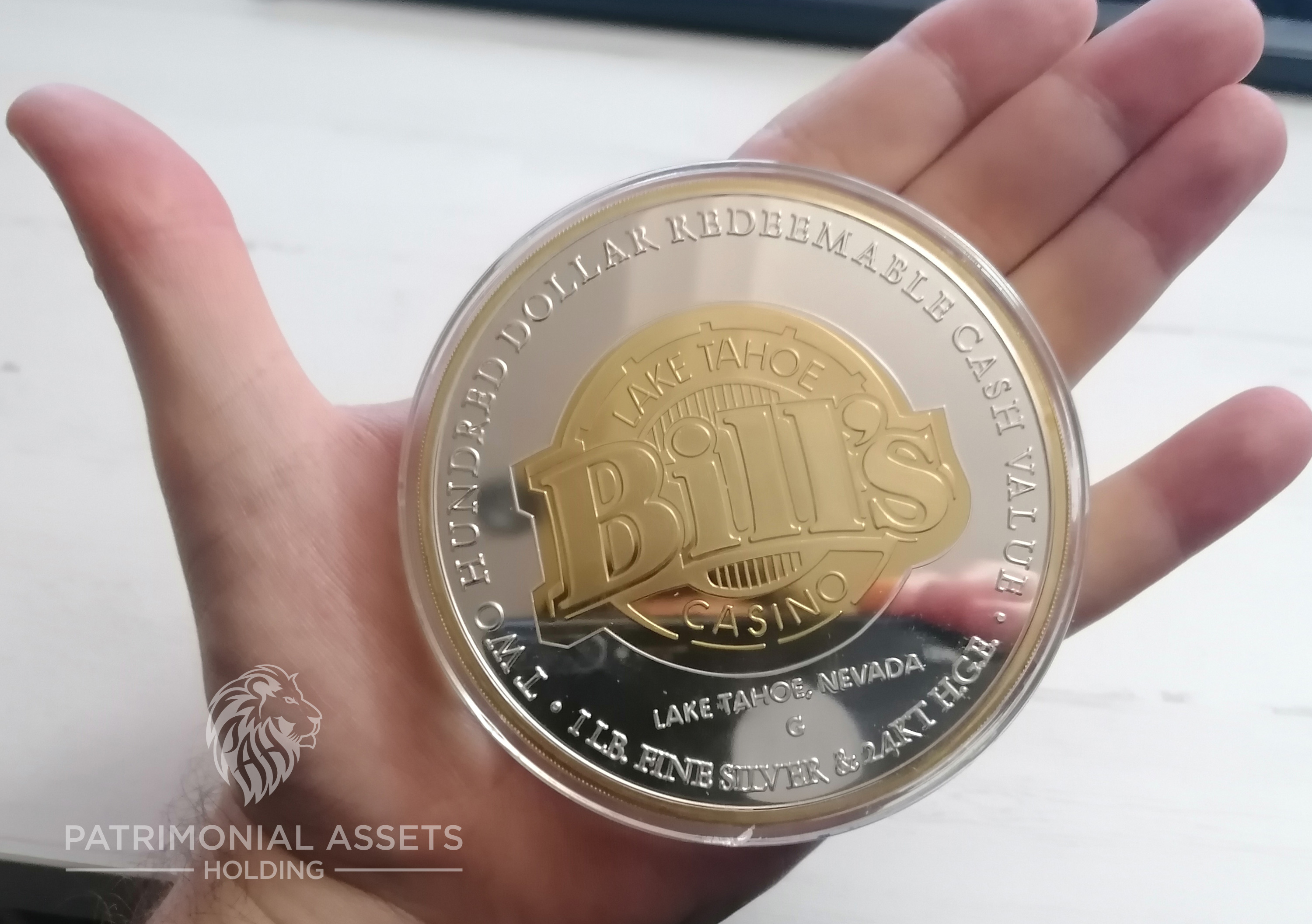 A man adult hand holding a $200 limited-edition casino token for visual comparation