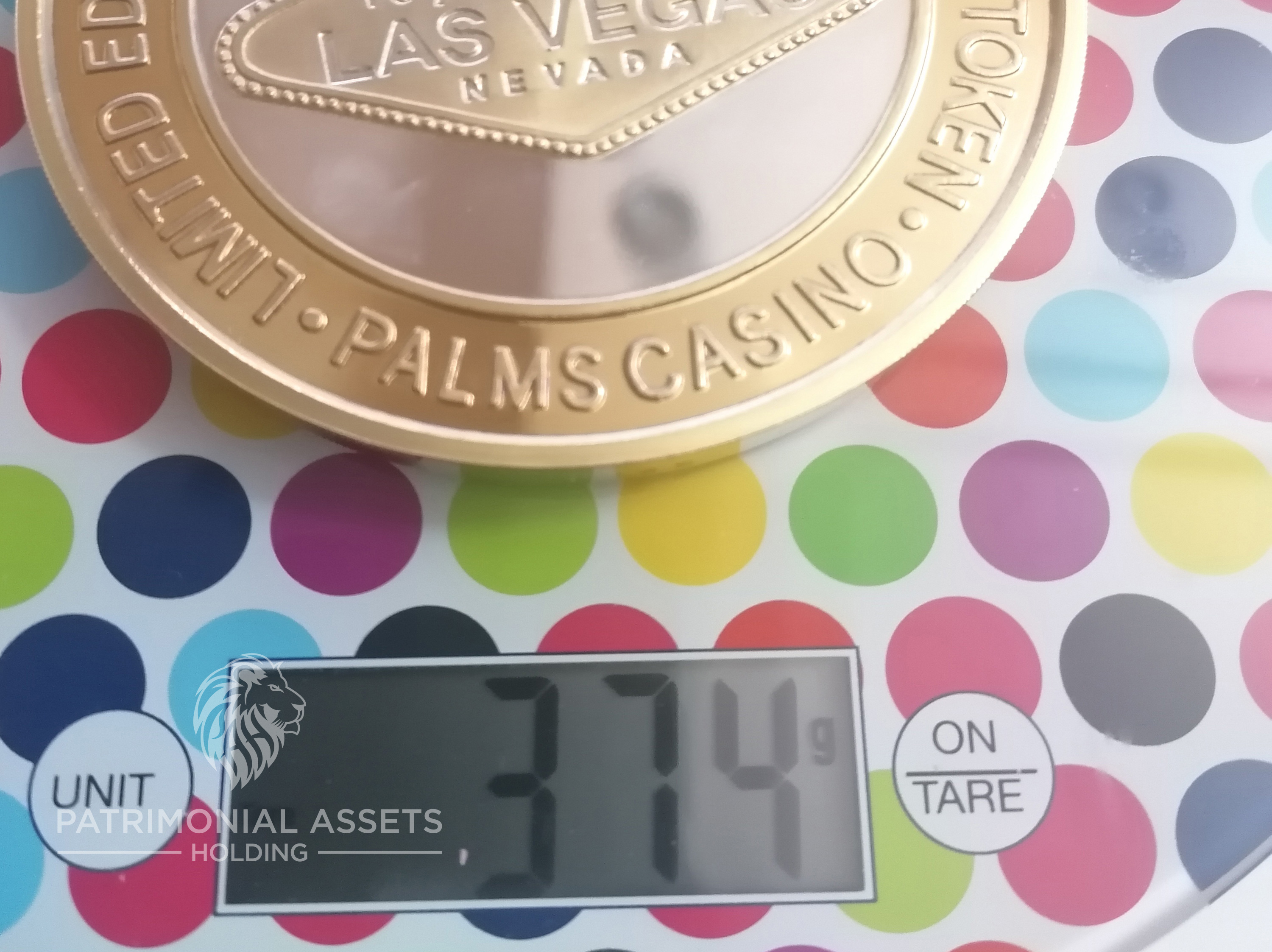 A casino token placed on a digital scale showing a weight of 374 grams equivalent to a 1 troy Pound (12 ounces)